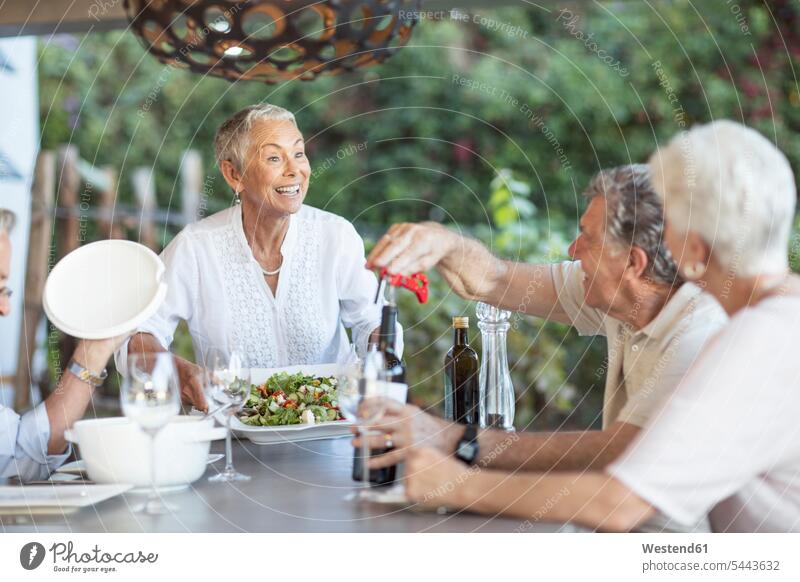 Lächelnde ältere Frau serviert Mittagessen auf der Terrasse Seniorin Seniorinnen alt Freunde Senioren weiblich Frauen Erwachsener erwachsen Mensch Menschen