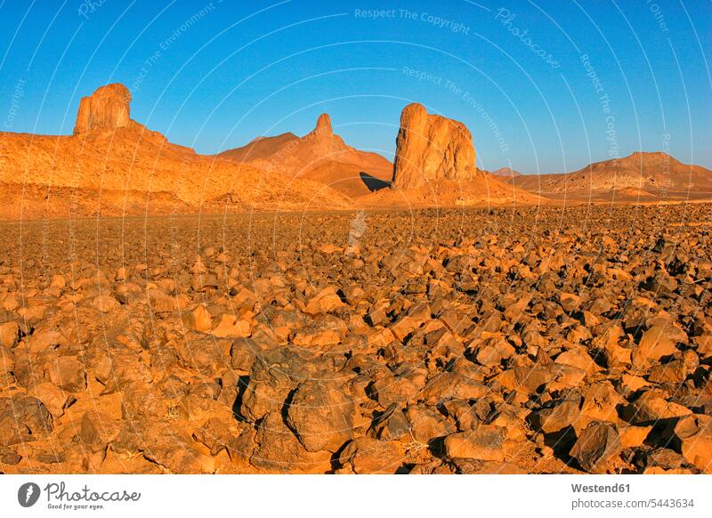 Algerien, Wilaya Tamanrasset, Hoggar-Gebirge, Atakor bei Sonnenlicht rötlich roetlich rot Felsformation Felsengruppe Gesteinsformation ländliches Motiv