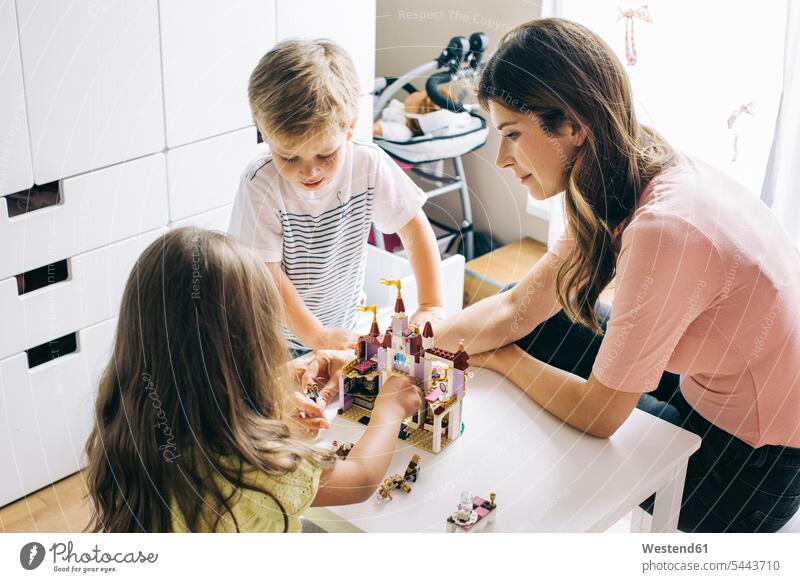 Mutter mit zwei Kindern baut zu Hause eine Spielzeugburg aufbauen Familie Familien spielen Mami Mutti Mütter Mama Mensch Menschen Leute People Personen Eltern