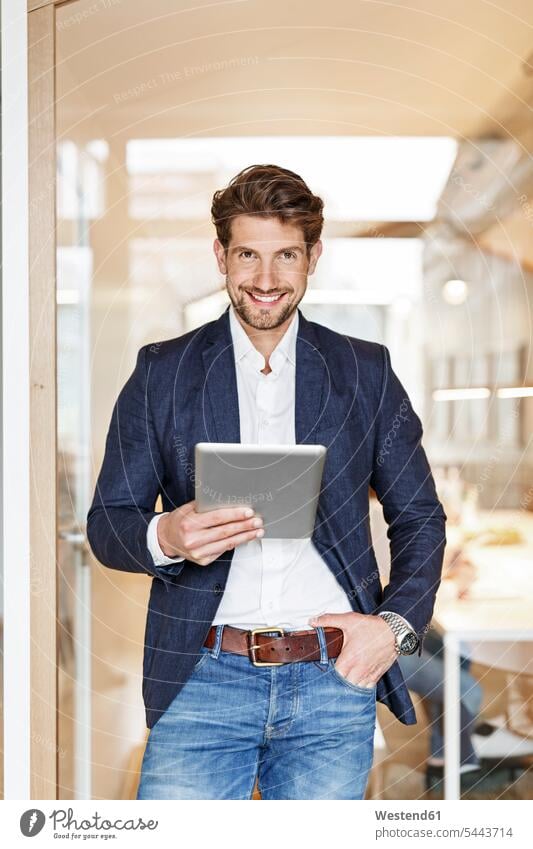 Porträt eines lächelnden Geschäftsmannes mit Tablett im Büro Tablet Computer Tablet-PC Tablet PC iPad Tablet-Computer Businessmann Businessmänner