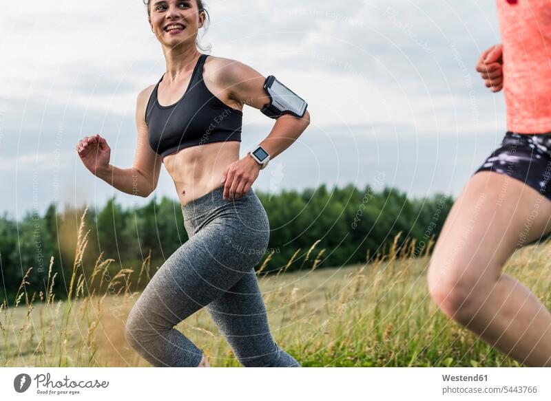 Zwei Frauen laufen auf dem Land lächeln rennen Joggen Jogging weiblich Freundinnen Fitness fit Gesundheit gesund Sport Erwachsener erwachsen Mensch Menschen