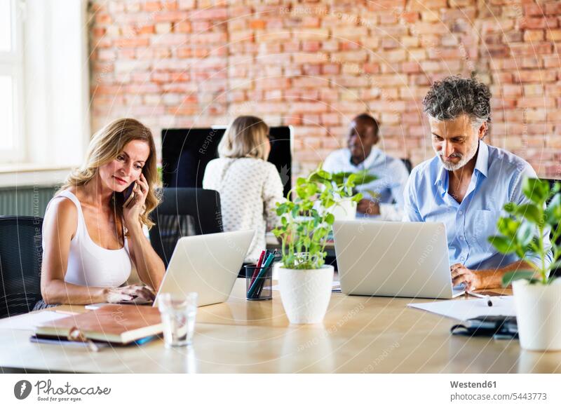 Geschäftsleute, die im Büro arbeiten, mit Smartphone und Laptop Geschäftspersonen Office Büros sitzen sitzend sitzt Start-up Startups Start ups Start-ups Arbeit