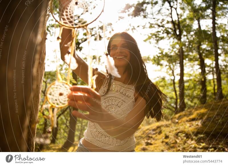 Glückliche Frau hängt Traumfänger an einem Baum Traumfaenger weiblich Frauen hängen lächeln Bäume Baeume glücklich glücklich sein glücklichsein Erwachsener