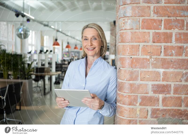 Reife Geschäftsfrau verwendet digitales Tablet stehen stehend steht lächeln Consulting reife Frau reife Frauen Geschäftsfrauen Businesswomen Businessfrauen