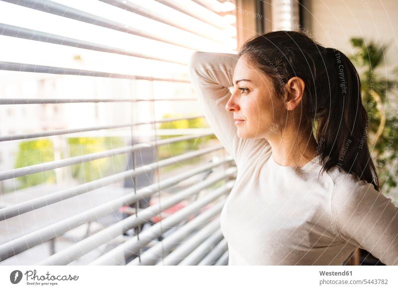 Frau zu Hause, die aus dem Fenster schaut schauen schauend anschauen betrachten weiblich Frauen sehend Erwachsener erwachsen Mensch Menschen Leute People