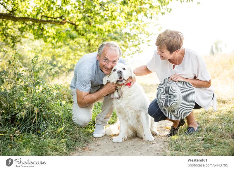 Älteres Ehepaar streichelt Hund im Freien lächeln Hunde Paar Pärchen Paare Partnerschaft Haustier Haustiere Tier Tierwelt Tiere Mensch Menschen Leute People