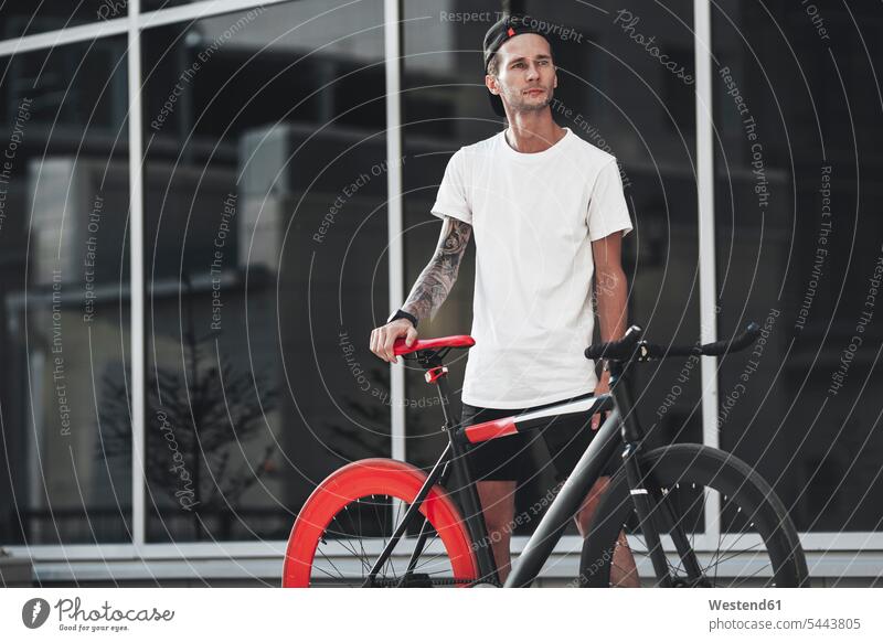 Junger Mann mit Fixie-Rad in der Stadt stehen stehend steht Fahrrad Bikes Fahrräder Räder Männer männlich Raeder Erwachsener erwachsen Mensch Menschen Leute
