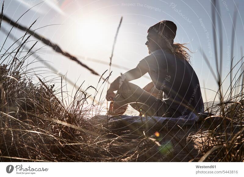 Portugal, Algarve, Mann sitzt bei Sonnenuntergang am Strand sitzen sitzend Beach Straende Strände Beaches Männer männlich Erwachsener erwachsen Mensch Menschen