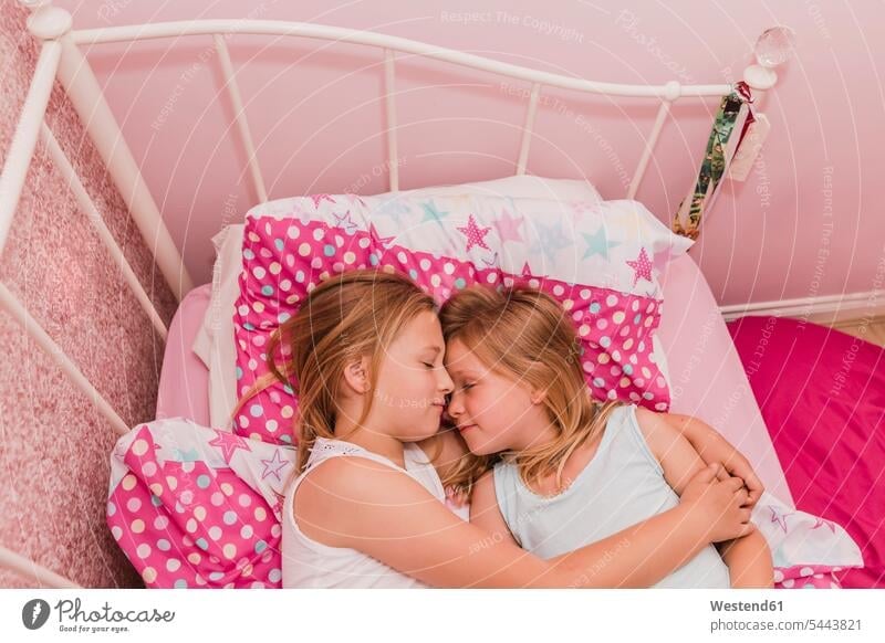 Zwei kleine Schwestern ruhen auf dem Bett Betten Mädchen weiblich Kind Kinder Kids Mensch Menschen Leute People Personen Geschwister Familie Familien