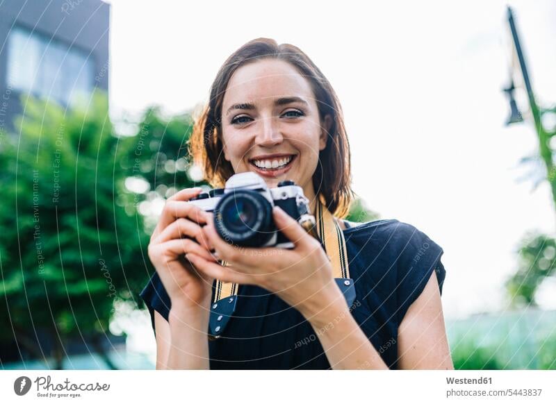 Porträt einer lächelnden Frau mit Kamera Fotoapparat Fotokamera Portrait Porträts Portraits weiblich Frauen Erwachsener erwachsen Mensch Menschen Leute People