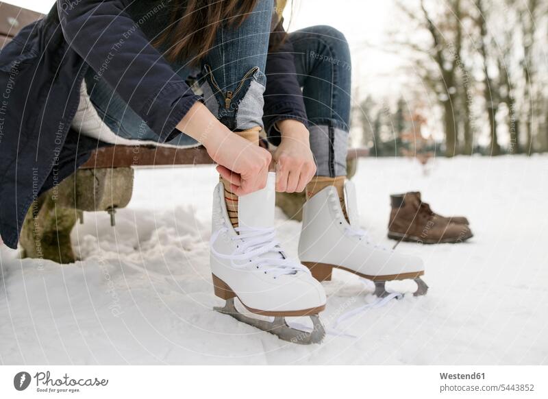Frau zieht ihre Schlittschuhe an Schlittschuhlaufen Eislaufen eislaufen schlittschuhlaufen anziehen anlegen Winter winterlich Winterzeit sitzen sitzend sitzt