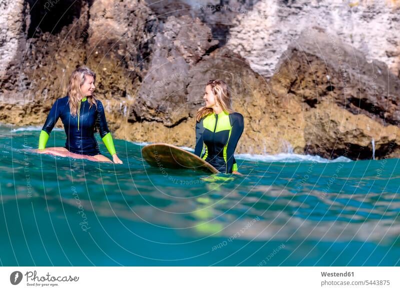 Indonesien, Bali, zwei lächelnde Frauen auf Surfbrettern Meer Meere weiblich Surfen Surfing Wellenreiten Gewässer Wasser Erwachsener erwachsen Mensch Menschen