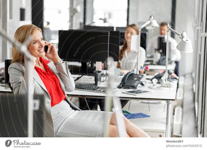 Geschäftsfrau am Schreibtisch im Büro am Mobiltelefon telefonieren anrufen Anruf telephonieren Geschäftsfrauen Businesswomen Businessfrauen Businesswoman
