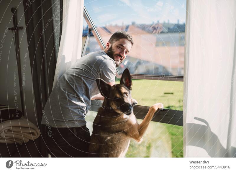 Junger Mann steht mit seinem Hund am Fenster und wartet jung Hunde Zuhause zu Hause daheim warten Männer männlich Haustier Haustiere Tier Tierwelt Tiere