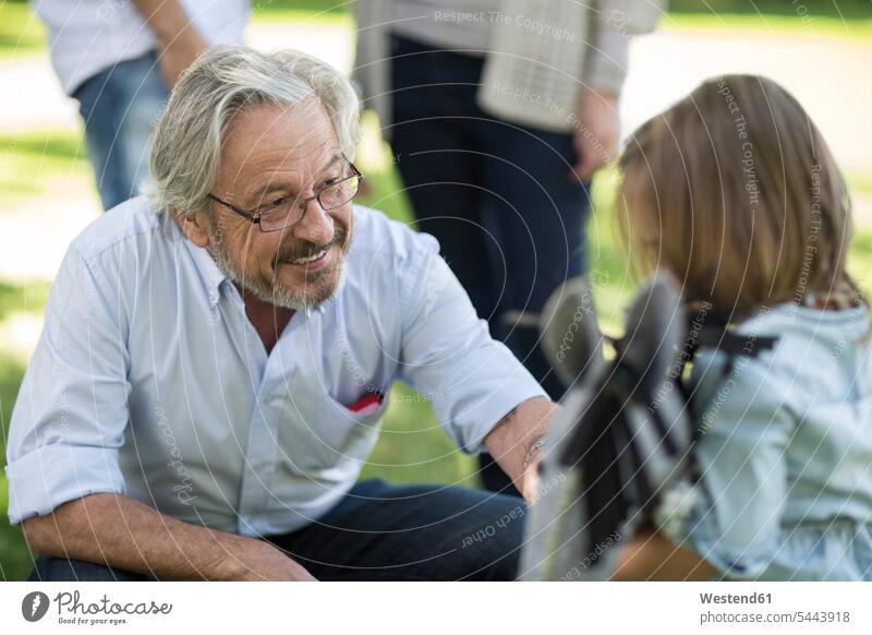 Lächelnder Großvater sieht Enkelin im Freien an lächeln Familie Familien Opa Großpapa Großpapas Opas Opi Großväter Opis Enkeltochter Enkelinnen Enkeltöchter