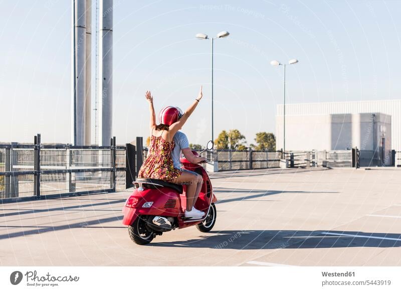 Unbeschwertes junges Paar fährt Motorroller auf Parkebene Parkdeck Parkdecks fahren Pärchen Paare Partnerschaft Sorglos glücklich Glück glücklich sein