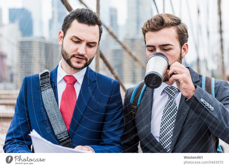 USA, New York City, zwei Geschäftsleute diskutieren über ein Dokument zur Brooklyn Bridge Geschäftsmann Businessmann Businessmänner Geschäftsmänner