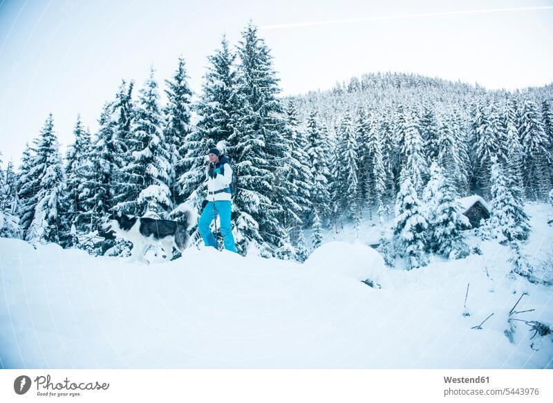 Österreich, Altenmarkt-Zauchensee, junge Frau mit Hund im Winterwald Hunde Ausflug Ausflüge Kurzurlaub Ausfluege winterlich Winterzeit weiblich Frauen Ski Skis