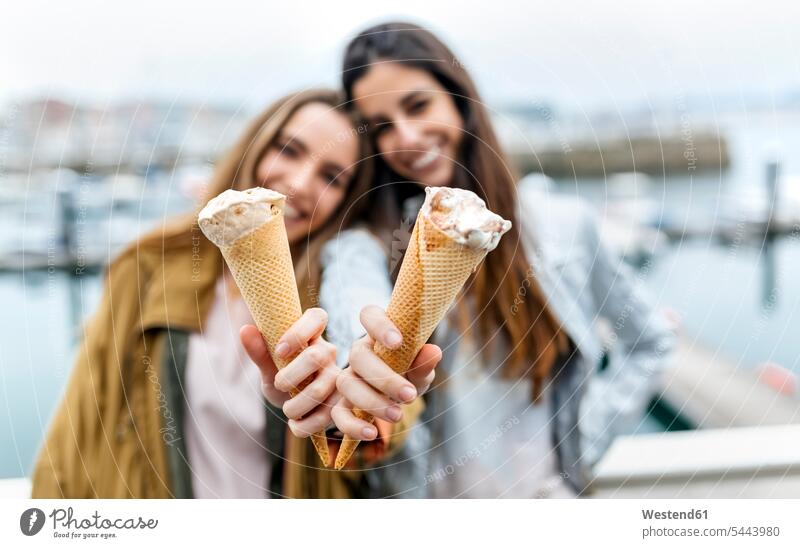 Zwei junge Frauen haben Spaß mit Eiscreme Speiseeis halten Spass Späße spassig Spässe spaßig Freundinnen Süßspeise Süsses Süßes süß Süßspeisen Essen Food