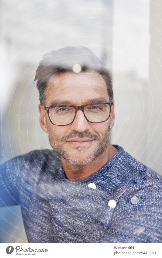 Porträt eines lächelnden Mannes hinter Glasscheibe mit Brille Portrait Porträts Portraits Männer männlich Glasscheiben Smart Brillen Erwachsener erwachsen