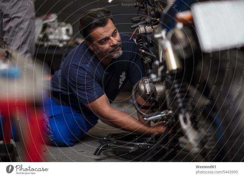 Mechaniker, der in der Werkstatt am Motorrad arbeitet Monteur arbeiten Arbeit reparieren Reparatur Motorräder Industrie industriell Gewerbe Industrien