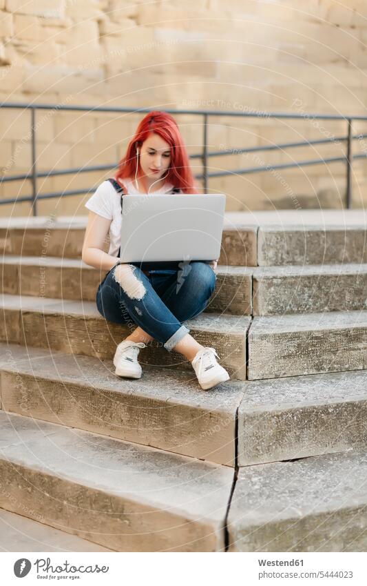 Rothaarige Frau sitzt mit Laptop und Kopfhörern auf der Treppe Notebook Laptops Notebooks weiblich Frauen Computer Rechner Erwachsener erwachsen Mensch Menschen