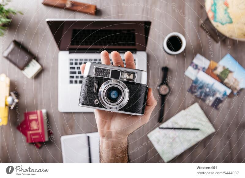 Draufsicht auf die Kamera in der Hand des Mannes und Reiseartikel auf dem Tisch Hände Fotoapparat Fotokamera Travel Laptop Notebook Laptops Notebooks Mensch