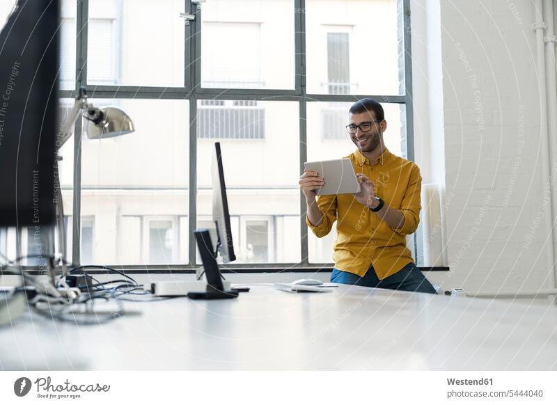 Junger Geschäftsmann im Büro mit digitalem Tablet Erfolg Erfolge erfolgreich Office Büros Businessmann Businessmänner Geschäftsmänner Agentur Agenturen lächeln