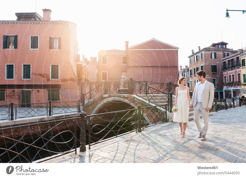 Italien, Venedig, Brautpaar geht bei Sonnenaufgang Hand in Hand Brautleute Brautpaare Ehepaar Ehepaare Ehen Mensch Menschen Leute People Personen glücklich