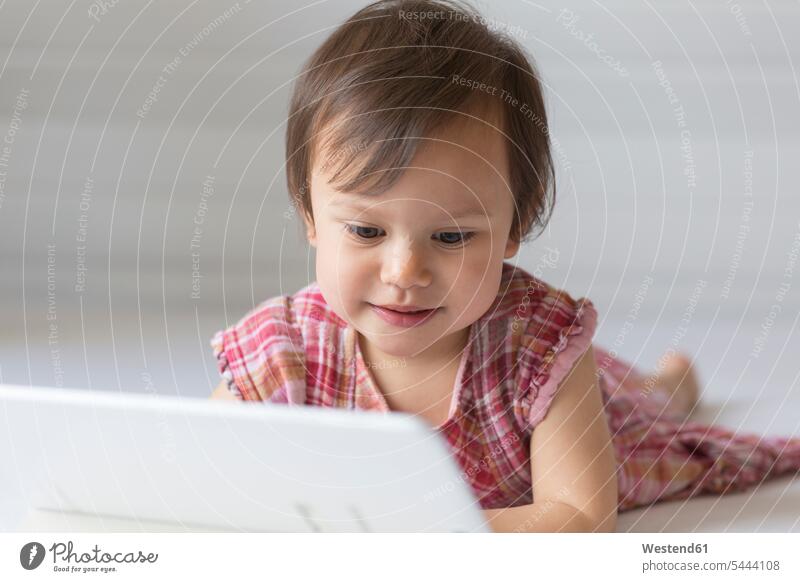 Porträt eines zufriedenen kleinen Mädchens, das auf ein digitales Tablet schaut weiblich Tablet Computer Tablet-PC Tablet PC iPad Tablet-Computer Kind Kinder