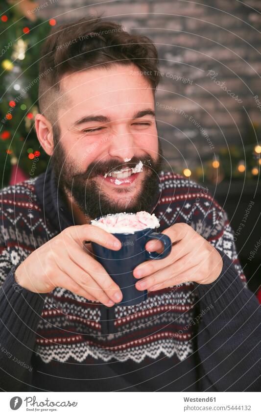 Porträt eines lachenden Mannes, der heiße Schokolade mit Schlagsahne und gehackten Zuckerstangen trinkt Portrait Porträts Portraits Männer männlich positiv