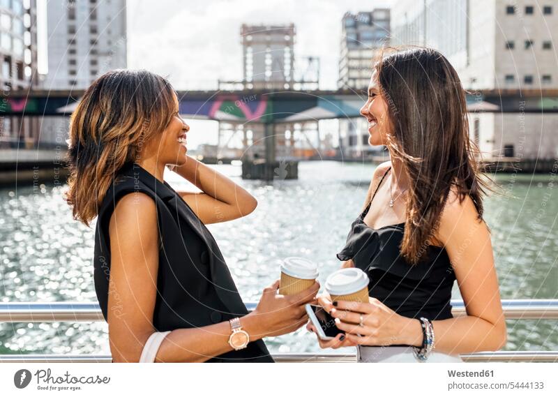 Zwei Frauen bei einer Kaffeepause auf einer Brücke in der Stadt lächeln weiblich Kollegin Kolleginnen Getränk Getraenk Getränke Getraenke Food and Drink