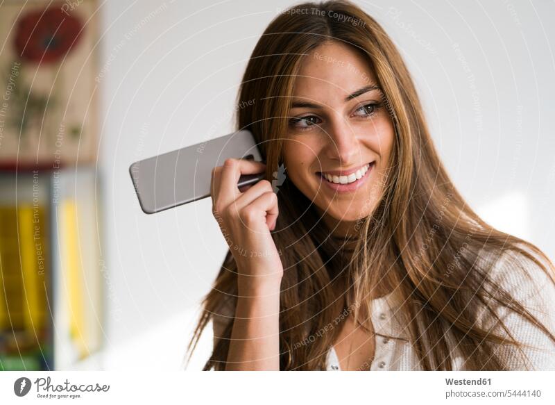 Lächelnde junge Frau mit Handy in der Hand Mobiltelefon Handies Handys Mobiltelefone weiblich Frauen lächeln Telefon telefonieren Kommunikation