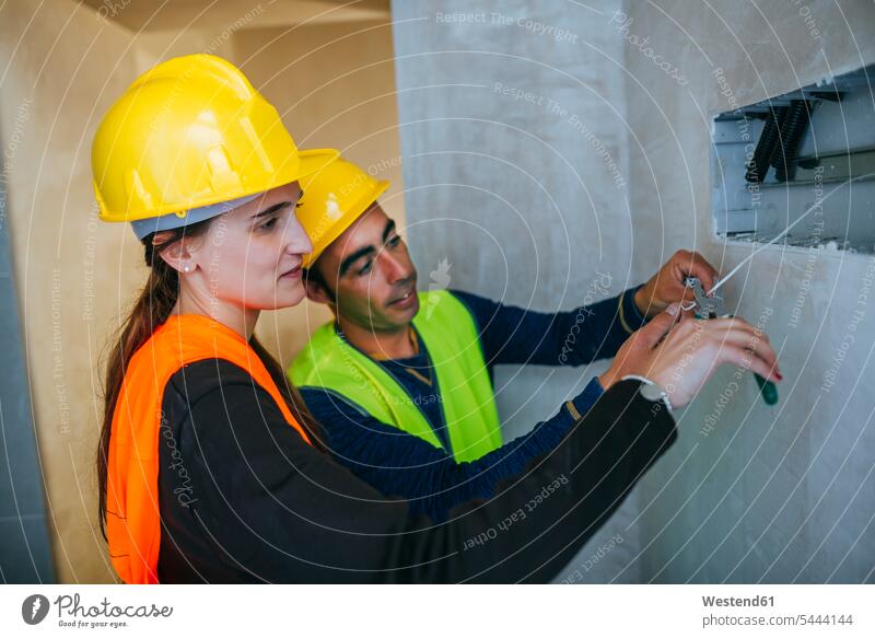 Männlicher und weiblicher Elektriker auf der Baustelle Baustellen arbeiten Arbeit Bauarbeiter Konstruktion konstruieren bauen Baugewerbe Handwerker