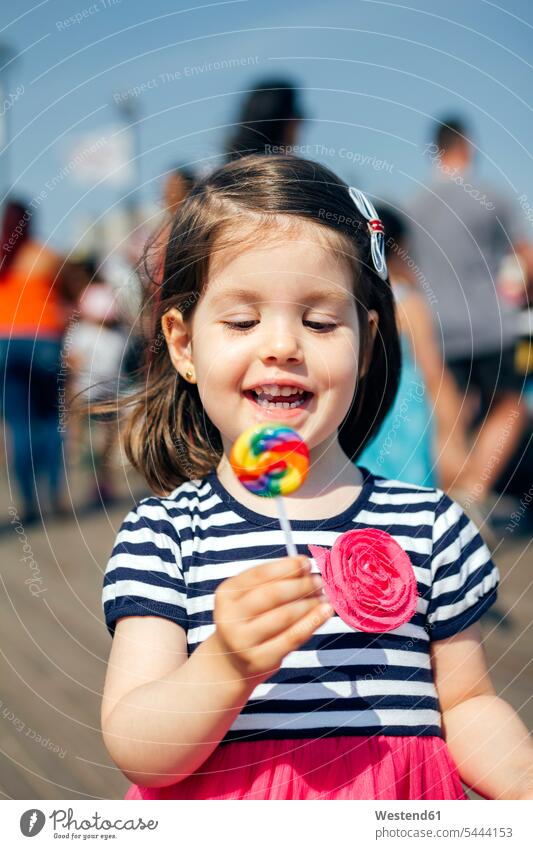 USA, New York, Coney Island, glückliches kleines Mädchen mit Lolli Lutscher Lollis Dauerlutscher weiblich Süßigkeiten Süßes Essen Food Food and Drink