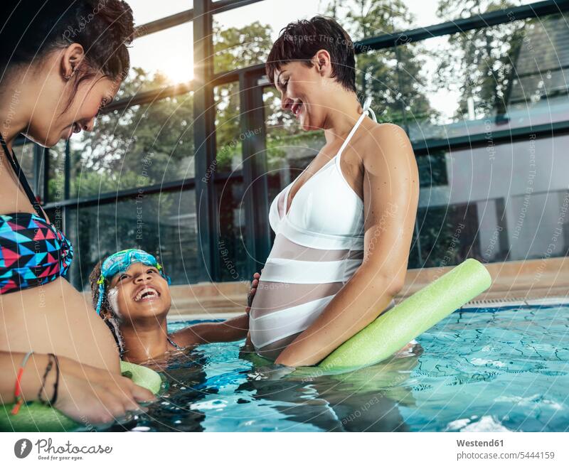 Zwei schwangere Frauen mit Tochter machen Wassergymnastik im Hallenbad Hallenbäder Hallenbaeder Schwimmbad Schwimmbaeder Schwimmbäder Schwangere weiblich