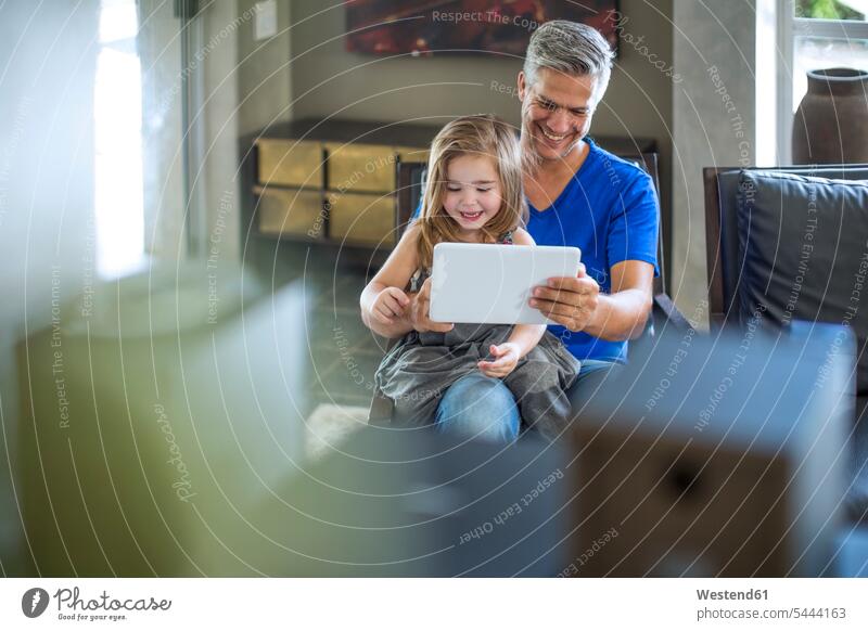 Vater und Tochter schauen auf das digitale Tablett Familie Familien Tablet Computer Tablet-PC Tablet PC iPad Tablet-Computer Zuhause zu Hause daheim lächeln