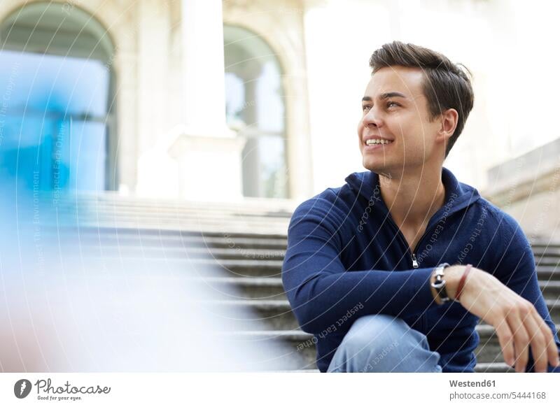 Porträt eines lachenden jungen Mannes auf einer Treppe sitzend Männer männlich Erwachsener erwachsen Mensch Menschen Leute People Personen Treppenaufgang sitzt