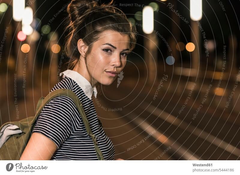 Porträt einer jungen Frau mit Rucksack, die nachts am Bahnhof wartet weiblich Frauen Nacht Erwachsener erwachsen Mensch Menschen Leute People Personen Rucksäcke