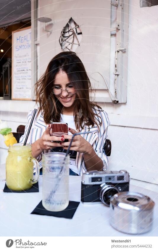 Junge Frau sitzt in einem Café und benutzt ein Smartphone Cafe Kaffeehaus Bistro Cafes Kaffeehäuser benutzen benützen weiblich Frauen iPhone Smartphones