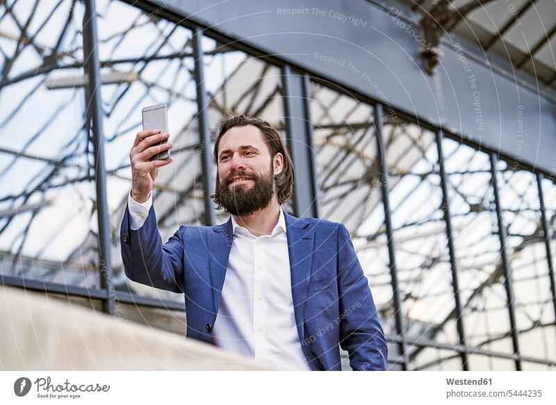 Lächelnder Geschäftsmann macht ein Selfie Selfies Handy Mobiltelefon Handies Handys Mobiltelefone lächeln Businessmann Businessmänner Geschäftsmänner Telefon