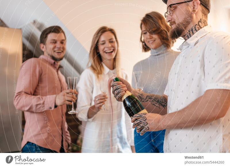 Mann öffnet Champagnerflasche, während seine Freunde zusehen Männer männlich Erwachsener erwachsen Mensch Menschen Leute People Personen Sektflasche