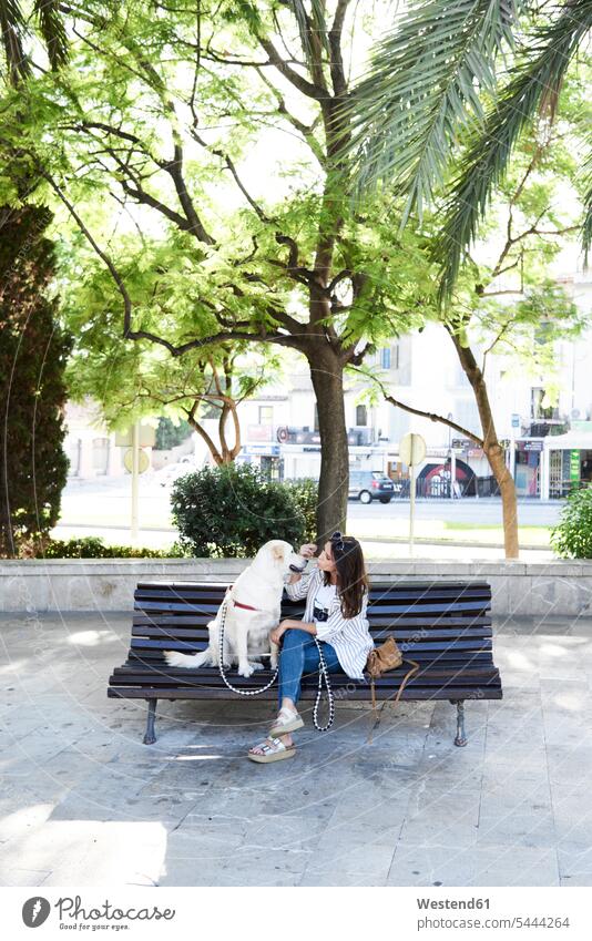Junge Frau sitzt mit ihrem Hund auf der Bank in der Stadt Hunde weiblich Frauen Sitzbänke Bänke Sitzbank sitzen sitzend staedtisch städtisch Haustier Haustiere