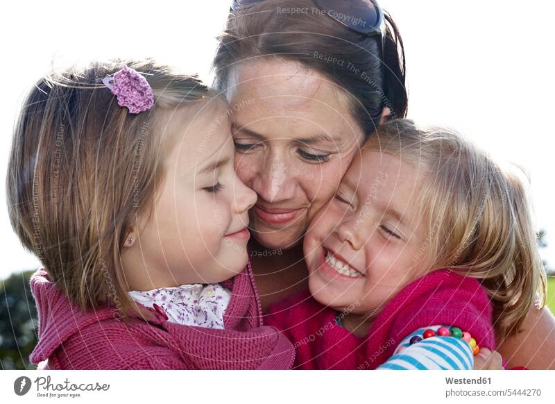 Mutter umarmt zwei Mädchen im Freien glücklich Glück glücklich sein glücklichsein weiblich Tochter Töchter Familie Familien Mami Mutti Mütter Mama Kind Kinder