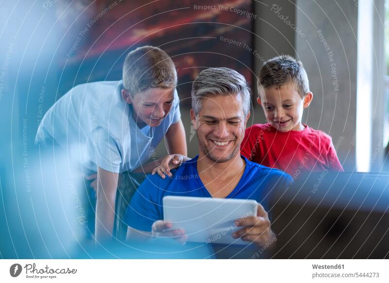 Kinder schauen mit ihrem Vater auf ein digitales Tablett Familie Familien Papas Väter Vati Vatis Papis lächeln Sohn Söhne Tablet Computer Tablet-PC Tablet PC