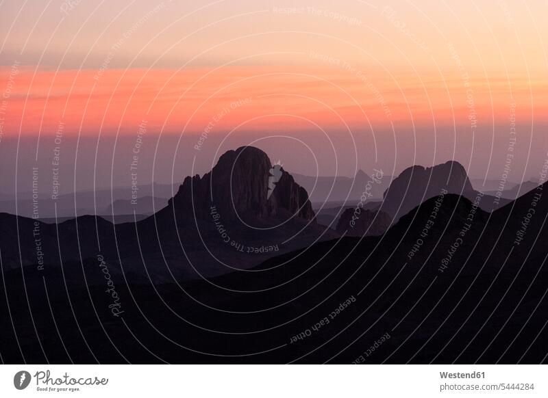 Algerien, Wilaya Tamanrasset, Hoggar-Gebirge mit Vulkangestein in der Dämmerung morgens Morgen früh Frühe Abendrot Abendroete Abendröte Ruhe Beschaulichkeit