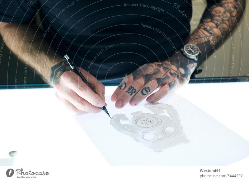 Tätowierer entwirft Motiv auf Leuchttisch im Studio Mann Männer männlich zeichnen Zeichnung Taetowierer entwerfen Entwurf Tattoo Tätowierungen Tatoos