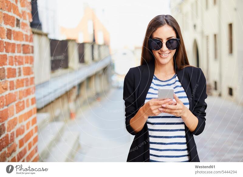 Junge Frau mit Sonnenbrille beim Telefonieren im Freien Handy Mobiltelefon Handies Handys Mobiltelefone lächeln weiblich Frauen telefonieren Kommunikation