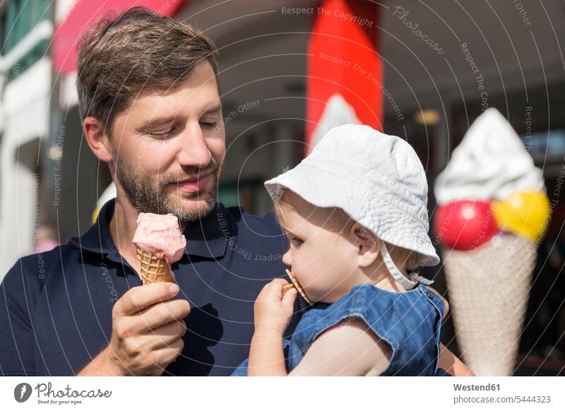 Vater isst Eiscreme und hält Tochter Töchter Speiseeis glücklich Glück glücklich sein glücklichsein ansehen Familie Familien essen essend Papas Väter Vati Vatis
