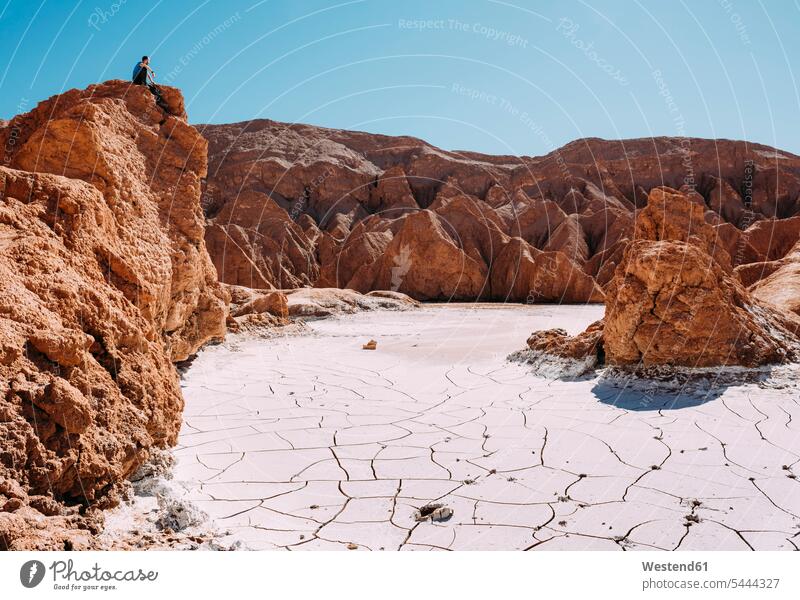 Chile, Atacama-Wüste, Mann sitzt auf einem roten Felsen und schaut zu betrachten betrachtend Männer männlich Wüsten schauen sehend Erwachsener erwachsen Mensch
